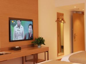 Cette chambre comprend un lit et une télévision murale. dans l'établissement GreenTree Inn Taizhou Taixing City Xuanbao Town Zhongyang Road Express Hotel, à Yong'anzhou