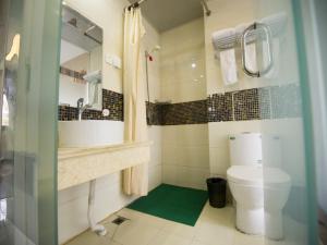 a bathroom with a sink and a toilet and a mirror at Shell Binzhou Bincheng District Yellow River Four Road Hotel in Binzhou