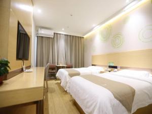 a hotel room with three beds and a flat screen tv at GreenTree Inn Dezhou Bus Station Train Station Express Hotel in Dezhou