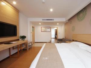 um quarto de hotel com uma cama grande e uma televisão de ecrã plano em GreenTree Inn Hefei Lujiang County Yihu West Road Chengxi No.4 Middle School Express Hotel em Lujiang