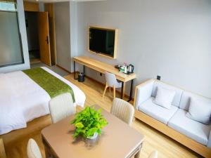 ein Hotelzimmer mit einem Bett, einem Sofa und einem Tisch in der Unterkunft GreenTree Inn Ankang Chengpeng Mechatronics CityBusiness Hotel in Xilingjing