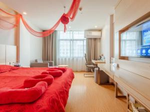 um quarto com uma grande cama vermelha e uma televisão de ecrã plano em GreenTree Inn LiuAn Huoshan County Yingjia Avenue County Hospital Express Hotel em Huoshan