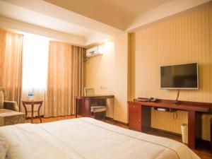 a hotel room with a bed and a desk with a television at GreenTree Inn Jiayuguan Xinhua South Road Express Hotel in Jiayuguan +21 photos