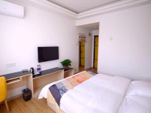 Schlafzimmer mit einem Bett, einem Schreibtisch und einem TV in der Unterkunft Shell Xingtai City Qiaodong DistrictXinhua South Road Hotel in Xingtai