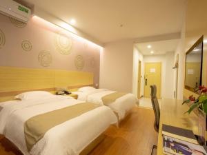 a hotel room with two beds and a television at GreenTree Inn Chizhou Shitai County Government Affairs New District Business Hotel in Chizhou