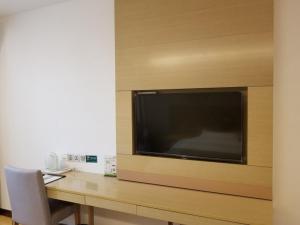 a desk with a large television on a wall at GreenTree Heze Changcheng Road Tianhua E-commerce Logistics Park Express Hotel in Heze