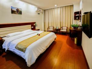 ein Hotelzimmer mit einem großen Bett und einem Schreibtisch in der Unterkunft GreenTree Inn JiangSu ChangZhou LiYang TianMu Lake Avenue TaiGang (W) Road Business Hotel in Liyang