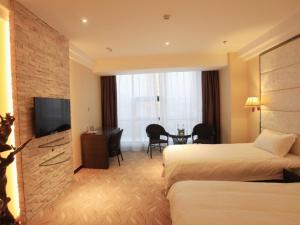 a hotel room with two beds and a flat screen tv at GreenTree Inn ShanDong North WeiHai StationNorth International Bathing Beach Business Hotel in Weihai +43 photos