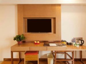 einen hölzernen Schreibtisch mit einem TV an der Wand in der Unterkunft GreenTree Inn Shandong Jinan Changqing District Changqing university town Express Hotel in Dangjiazhuang + 43 Fotos