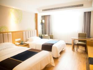 una camera d'albergo con due letti e un tavolo di GreenTree Inn JiangSu Taizhou Taixing Middle Guoqing Road Business Hotel a Taixing