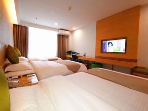 a hotel room with three beds and a flat screen tv at GreenTree Inn Shanxi Baoji Fengxiang Donghu Business Hotel in Zhifang
