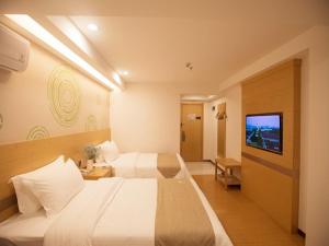 a hotel room with two beds and a flat screen tv at GreenTree Inn Haikou Chengmai Old Town Software Park Business Hotel in Bailian