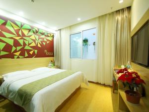 ein Schlafzimmer mit einem großen Bett und einem Fernseher in der Unterkunft VaticaWuxi Huishan District Western Shengan Road Baile Square Hotel in Wuxi