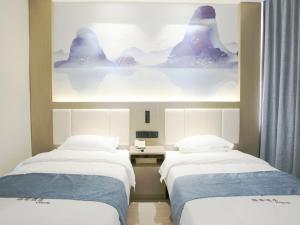 twee bedden in een hotelkamer met een schilderij aan de muur bij VX hotel Nanjing South Railway Station Daming Road Metro Station in Nanjing