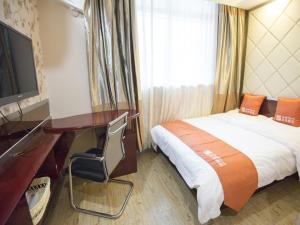 ein Hotelzimmer mit einem Bett, einem Schreibtisch und einem TV in der Unterkunft Shell Dingxi County Minzhou East Road Hotel in Min