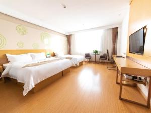Zhuozhou的住宿－格林豪泰保定市涿州市火车站商务酒店，一间卧室配有两张床、一张桌子和一台电视。