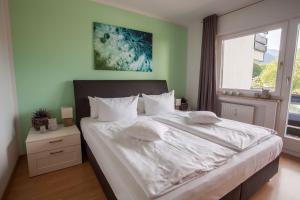 a bedroom with a large bed with white sheets and a window at Alpenglühen Whg. 21 in Garmisch-Partenkirchen