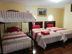 a bedroom with two bunk beds with red and white blankets at Hotel Navarra in Riobamba