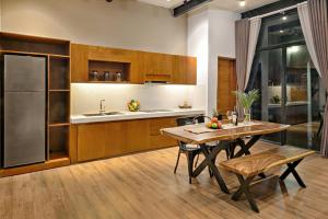 a kitchen with a table and a refrigerator at Sense Villa by Enspired Vietnam in Da Nang