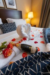 Una botella de vino y toallas en una cama con rosas. en Bayview Hotel en Courtenay