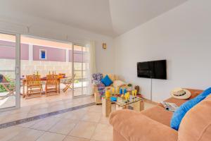 ein Wohnzimmer mit einem Sofa und einem TV in der Unterkunft Villa Aloe con piscina climatizada, Playa Fañabe, Costa Adeje in Adeje