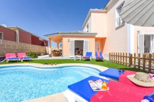 einen Pool mit Liegestühlen und ein Haus in der Unterkunft Villa Aloe con piscina climatizada, Playa Fañabe, Costa Adeje in Adeje