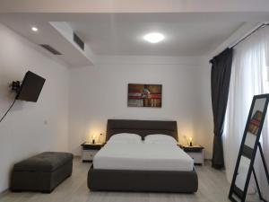 a bedroom with a bed and two tables and a chair at E&A Apartments Guesthouse in Durrës