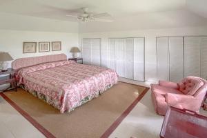 a bedroom with a pink bed and a chair at Coral Sea private beachfront panorama with infinity pool in Tuckerʼs Town