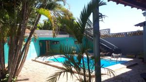 a blue house with a swimming pool and palm trees at Hotel Pousada Jaguariuna in Jaguariúna
