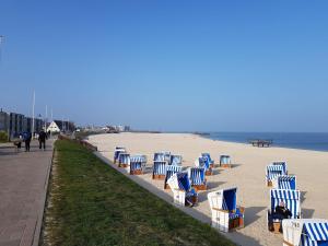 a row of blue and white chairs on the beach at Appartement-Leuchtturmblick in Hörnum