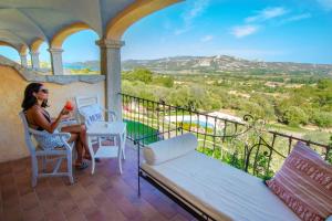 a woman sitting at a table on a balcony with a drink at Moma Hotel Cannigione in Cannigione
