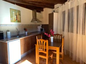 cocina con mesa, sillas y fregadero en Casa rural LA DEHESA, en Cilleros