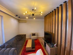 een woonkamer met een bank en een televisie bij Mel’s Place in Tirana