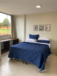 a bedroom with a bed with blue sheets and a window at Delú Residences in Alto Paraíso de Goiás