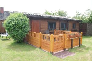 a wooden fence in front of a cabin at Haus Seerobbe-Blockhaus im Garten in Fehmarn +4 photos