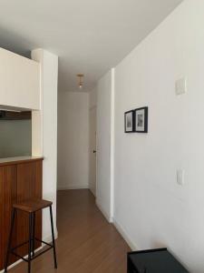 a living room with a stool and a white wall at Apto aconchegante ao lado do Shopping Pamplona, Jardim Paulista. in São Paulo