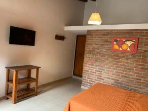 ein Schlafzimmer mit einem Bett und einer Ziegelwand in der Unterkunft Cabañas Bosques del Centro in Mina Clavero