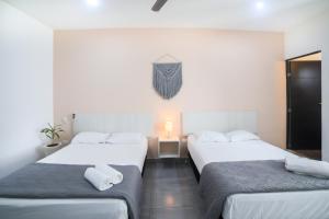2 camas en una habitación de hotel con paredes blancas en Almond Suites en Playa del Carmen