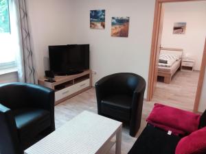 a living room with two chairs and a flat screen tv at Amera-Ferienwohnung in Lübeck