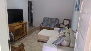 un salon avec un canapé et une télévision à écran plat dans l'établissement Casa com Piscina 200 m da Praia - São Sebastião, à São Sebastião