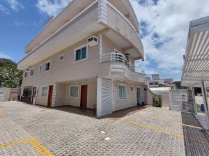 Cette grande maison blanche dispose d'un balcon. dans l'établissement Residencial Batista, à Bombinhas