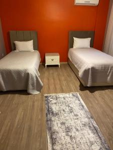 twee bedden in een kamer met een oranje muur bij Bahçe'de Villa in Sapanca