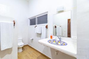 a white toilet sitting next to a sink in a bathroom at Hotel & Suites Oasis Bacalar in Bacalar