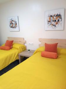 two beds with yellow and red pillows in a room at Casa Albeniz. in Algeciras