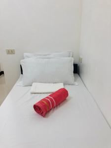 a red towel laying on a white bed at LR Hostel and Cafe in Moalboal