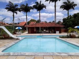 a pool with a slide in front of a house with palm trees at Chalé aconchegante na Serra Pernambucana - Em condomínio - Gravatá in Gravatá