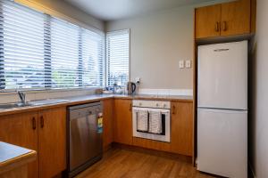 Una cocina con gabinetes de madera y un refrigerador blanco. en *** LAKE VILLA 461 ***, en Hanmer Springs