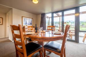 Un comedor con mesa y sillas y una gran ventana. en *** LAKE VILLA 461 ***, en Hanmer Springs