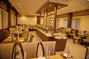 a restaurant with tables and chairs and a bar at Hotel Prince Gardens in Coimbatore