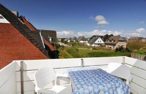 einen Balkon mit einem Tisch und 2 weißen Stühlen in der Unterkunft Wohnung re. Sylter Boje in Wenningstedt-Braderup